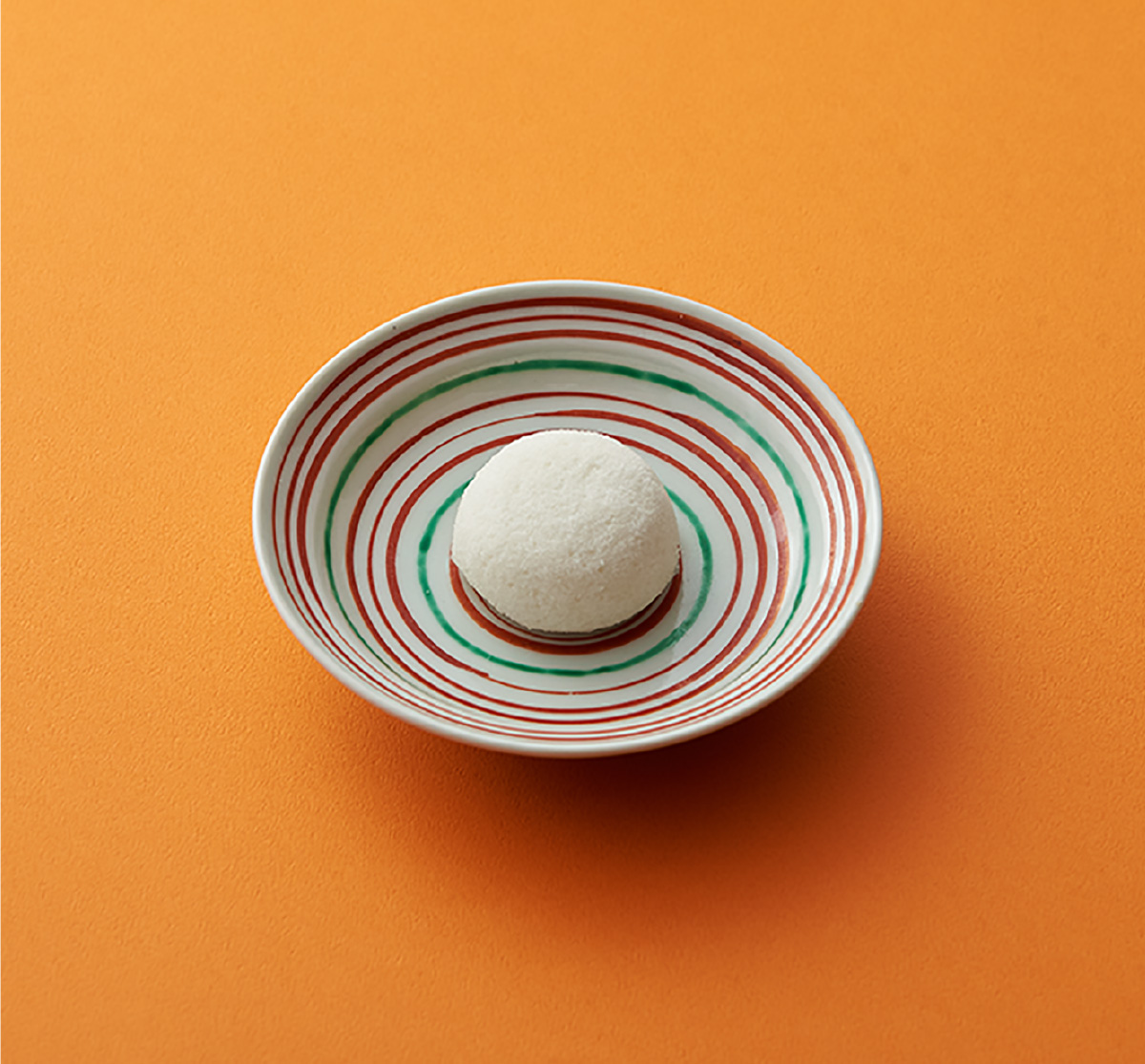オレンジ色の背景と色絵皿の上の山芋かるかん饅頭
