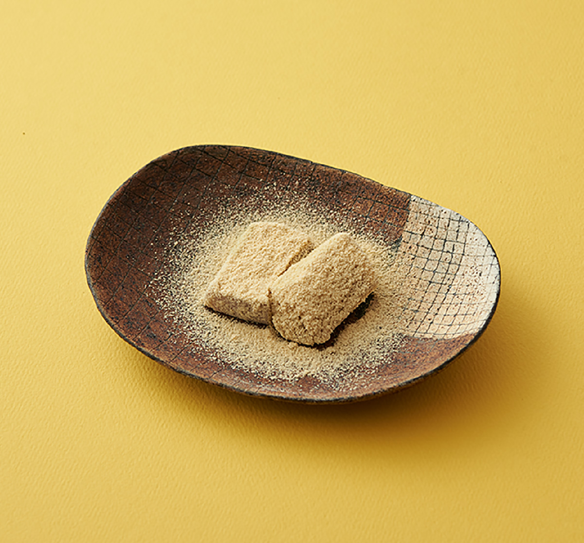 黄色い背景と和皿の上の元祖きび餅